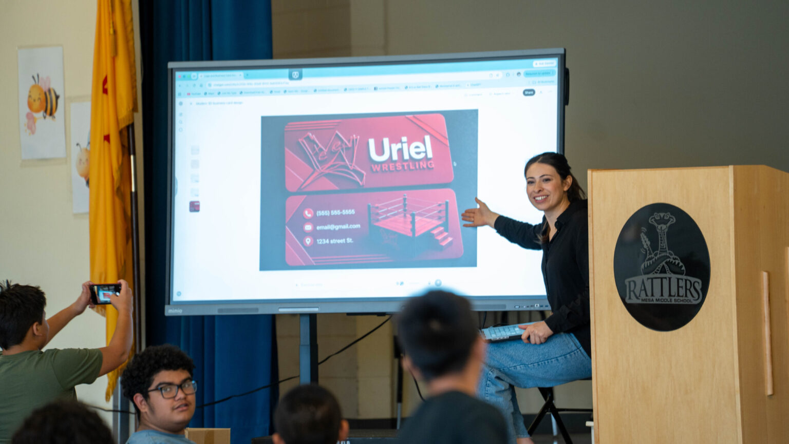 Raquel Madrigal showing a student's business card design on screen during a creative entrepreneurship workshop
